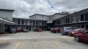 A parking lot with several cars and a building with multiple floors and balconies. - Cindy Lyn Motel (Cicero)