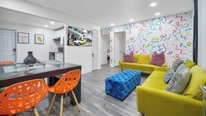 A modern living room with a yellow sofa, orange chairs, and a blue ottoman. - Good Vibes Retreat Decor BBQ Patio heart Wynwood (Miami)