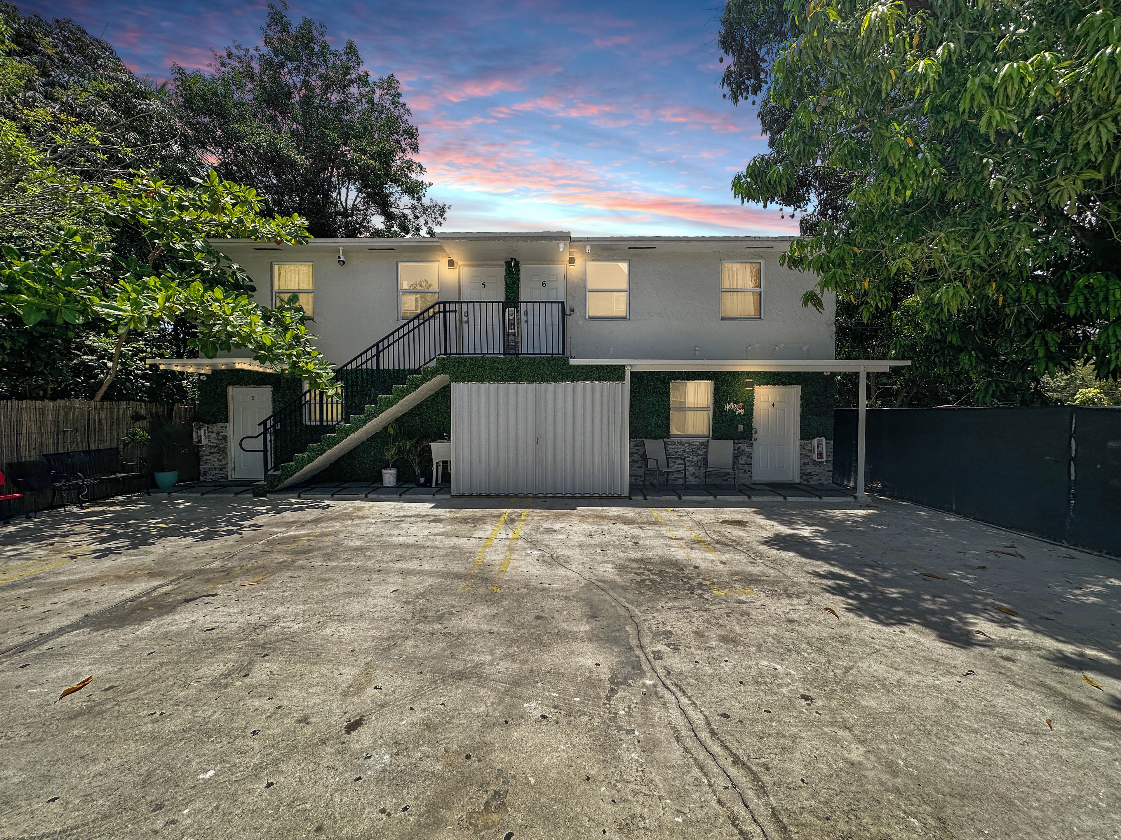 A two-story house with a covered patio area, a staircase, and a fenced yard.