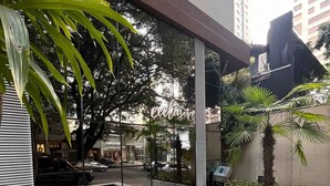 A swimming pool with a tiled floor, surrounded by plants and a building with a sign that reads "edilizia". - Lockings  Lourdes 12 (Belo Horizonte)