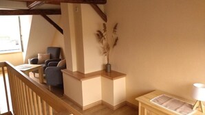 A cozy room with a wooden staircase, a seating area with a sofa and chairs, and a small table. - Narrow & tall - Welcome to the narrowest house in Bad Frankenhausen (Bad Frankenhausen/Kyffhäuser)