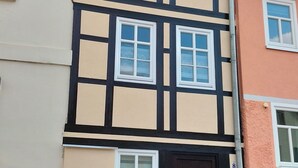 A two-story building with a dark brown door, multiple windows, and a brick chimney. - Narrow & tall - Welcome to the narrowest house in Bad Frankenhausen (Bad Frankenhausen/Kyffhäuser)