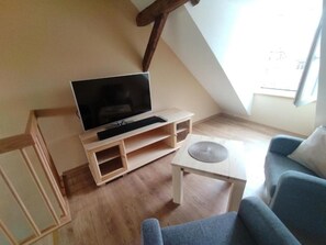 En stue med et fjernsyn på et træstel, et sofabord og to sofaer.