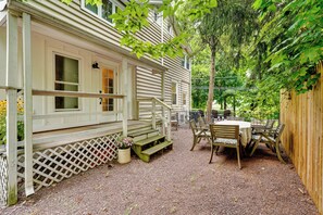 A covered porch with a wooden bench and a table with chairs, surrounded by a wooden fence and trees. - Upper Black Eddy Home w/ Delaware River Access! (Upper Black Eddy)