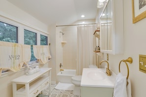 Ein Badezimmer mit Badewanne, Toilette und Waschbecken. Handtücher hängen an der Wand, und ein Waschtisch mit Schubladen ist ebenfalls vorhanden.