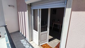 A covered outdoor area with a sliding glass door leading to a room with a table and chairs. - Lisbon traditional T2 with balcony in Damaia (Amadora)