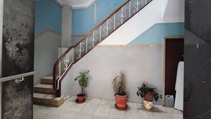 A staircase with a wooden handrail and decorative balusters, flanked by potted plants on a tiled floor. - Lisbon traditional T2 with balcony in Damaia (Amadora)