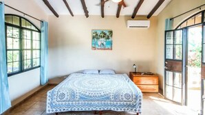 Un dormitori amb un llit, un ventilador de sostre, un quadre i una finestra.