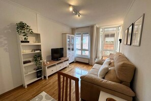 A living room with a sofa, TV, shelves, and a window. - 632A Beautiful Apartment in Oviedo by R2R (Oviedo)