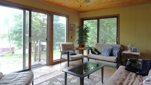 Un salon spacieux doté d’un ventilateur de plafond, de grandes fenêtres, d’un canapé, d’un fauteuil et d’une table basse.
