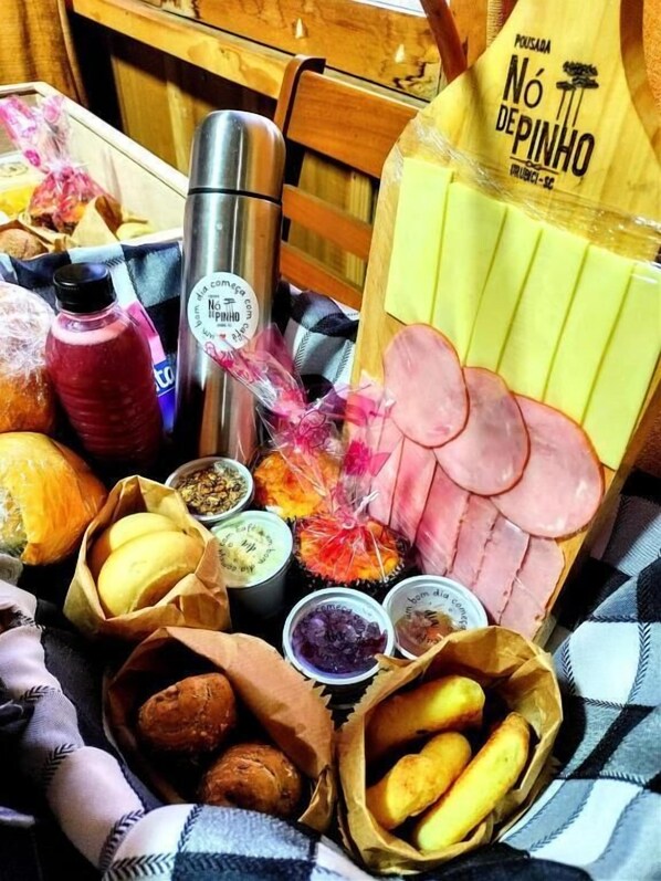 Una mesa con diversos alimentos, como pan, jamón y un termo.