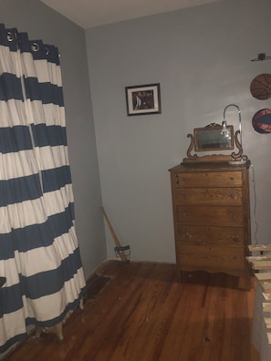 A room with a wooden dresser, a framed picture on the wall, and a basketball hoop.