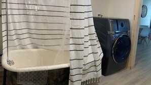 Un baño con una bañera antigua, una lavadora y una puerta de madera.