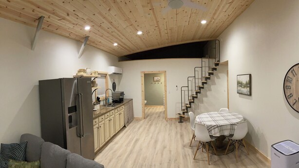 Un espacio habitable compacto con kitchenette, comedor y una escalera que conduce a un nivel superior.