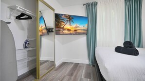 Ein Hotelzimmer mit Bett, einem Sonnenuntergangsbild, einem Kleiderschrank und einem Spiegel.