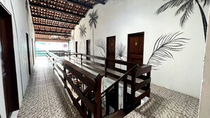 A hallway with a wooden bench, a tiled floor, and walls with palm tree murals. - Toca do pato hospedagem (Paraty)