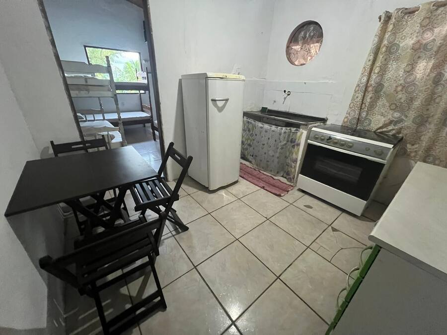 A compact kitchen with a dining table, chairs, a refrigerator, a stove, and a small window.