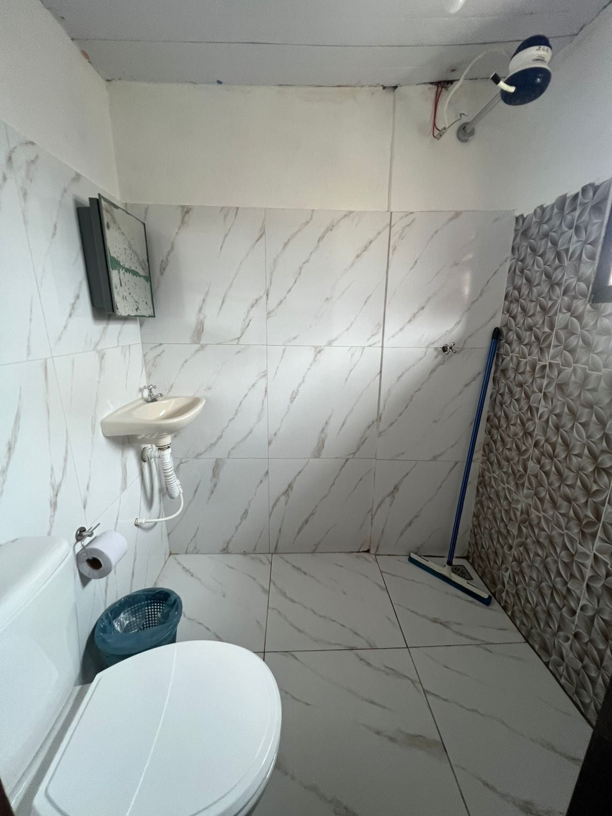 A bathroom with a toilet, sink, and shower area.