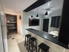 A compact kitchen with a bar area, a microwave, and a small refrigerator. - Toca do pato hospedagem (Paraty)