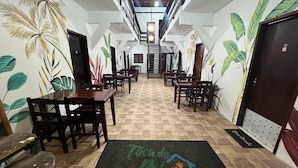 A hotel lobby with a checkered floor, wooden tables and chairs, and walls decorated with tropical leaf patterns. - Toca do pato hospedagem (Paraty)