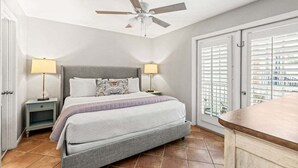 Una camera da letto con un letto, comodini, una ventola a soffitto e vista attraverso una porta.