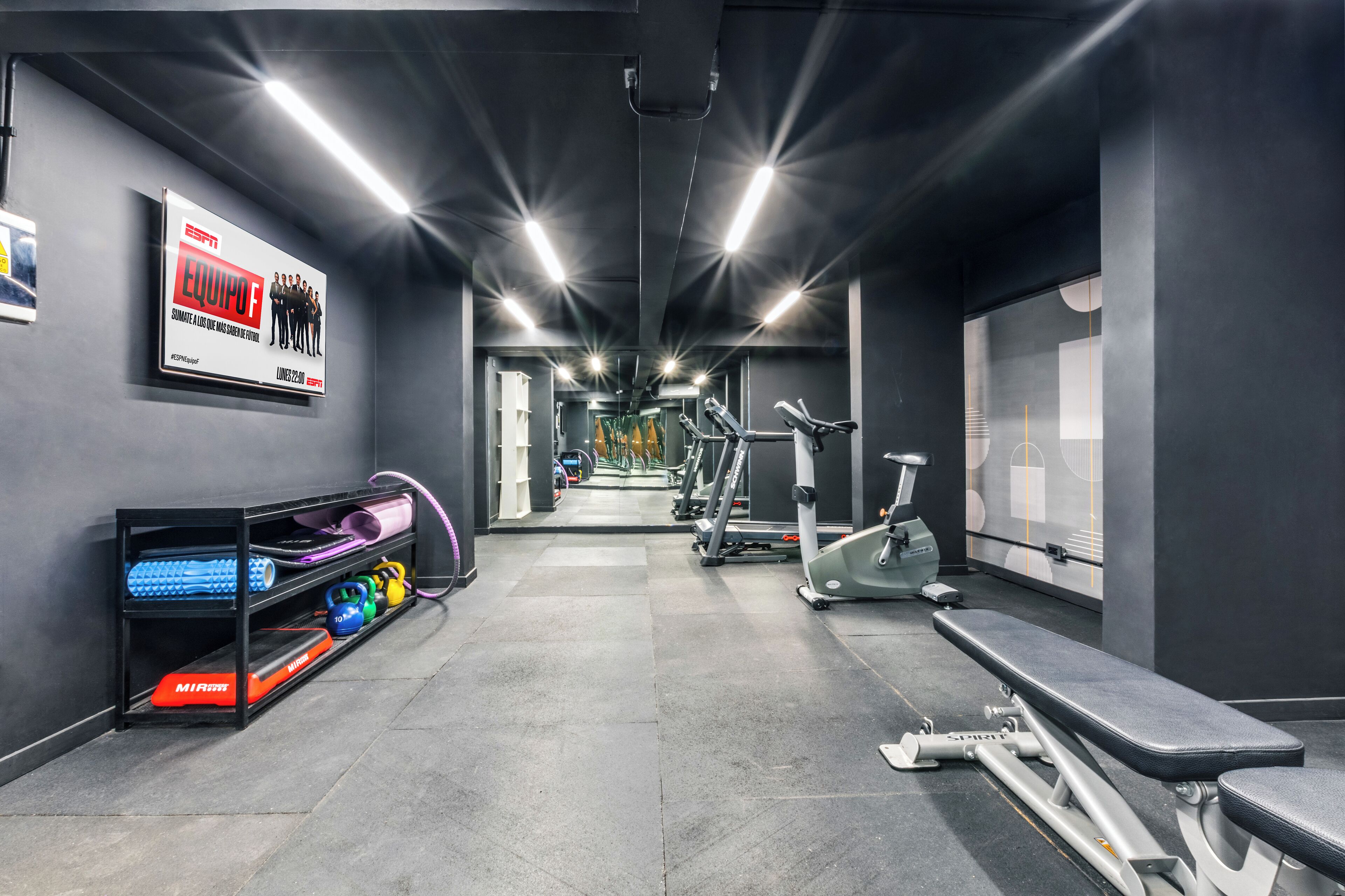 Une salle de sport équipée de tapis de course, de vélos elliptiques et de matériel de musculation.