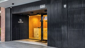 En moderne hotelindgang med en sort facade, en receptionsdisk i marmor, og navnet 'HAUSTON' er synligt.