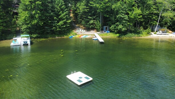 A calm river with a dock and kayaks. - The Cub Hill Chalet on Cub Lake - Private Lakefront, Dock, Raft, Water Toys, Huge Deck, and Spa! (Kalkaska)