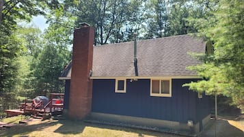 Un petit bâtiment d’un seul étage, à l’extérieur d’un bleu foncé, avec une cheminée en briques et un toit en pente.