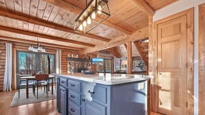 A wooden cabin interior with a kitchen island, dining area, and a large wooden door. - The Hillside Hideaway at Crystal Lake - Gorgeous with Great Outdoor Deck and Spa! (Beulah)