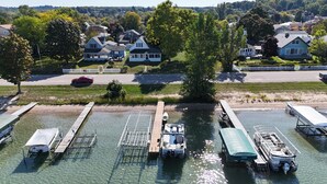 A marina with boats docked, a clear waterway, and houses in the background.