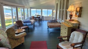 A cozy room with a bed, chairs, a table, and a view of the ocean.