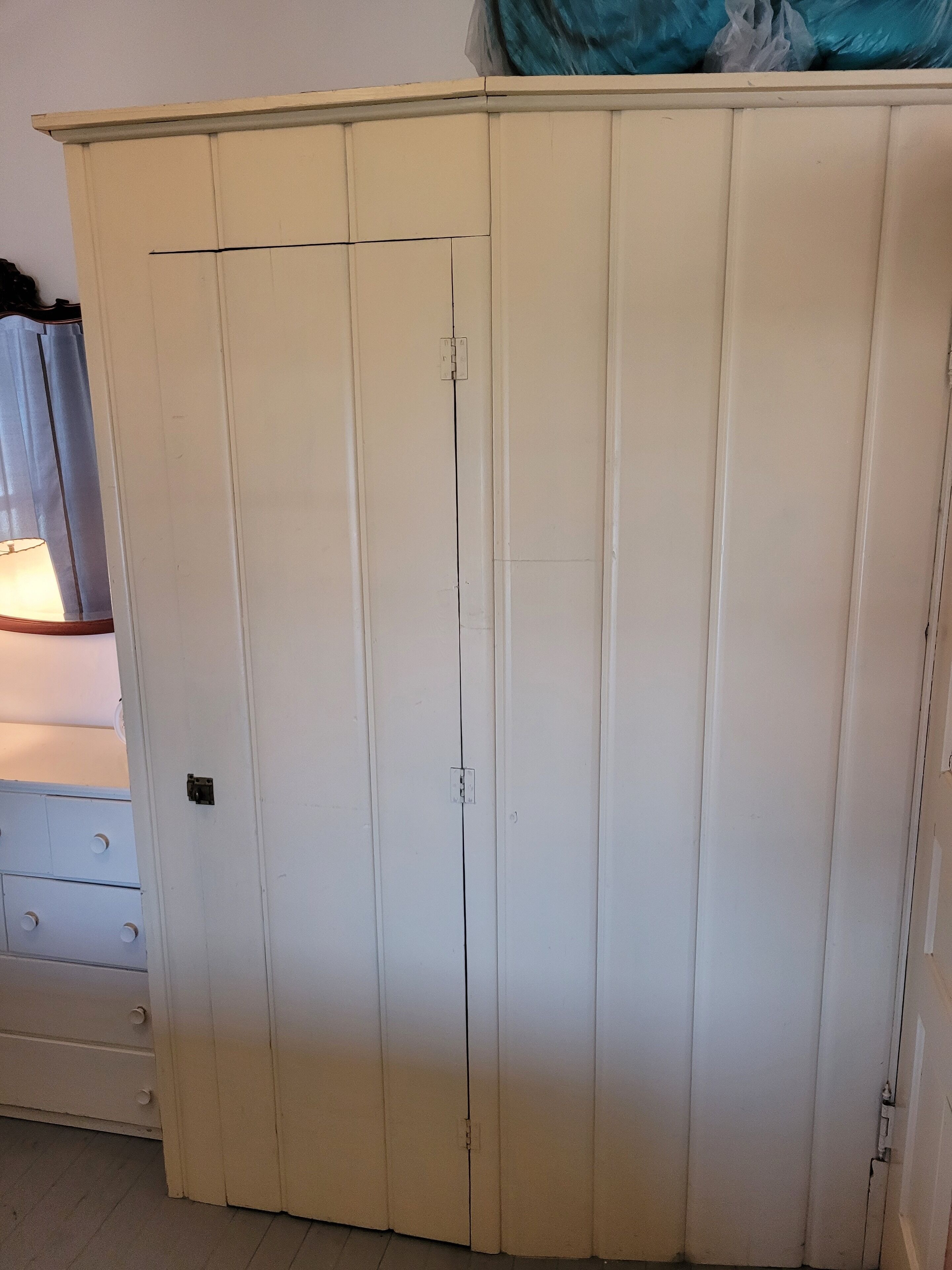 A white wardrobe with a single door and a small shelf.