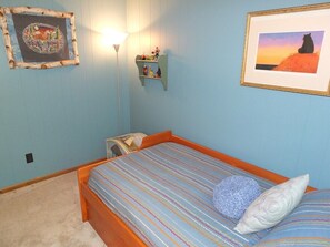 Ein Schlafzimmer mit Bett, Nachttisch, Lampe und Wanddekorationen.