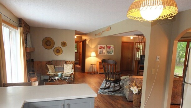 A spacious living area with a kitchen, dining table, and seating. - The Maple Cottage - WALK TO BEACH, LAKE MICHIGAN, AND DOWNTOWN! (Frankfort)
