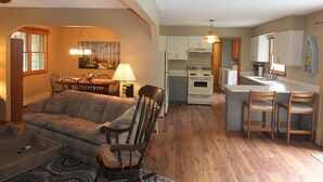 A compact living space with a dining area, kitchen, and seating area. - The Maple Cottage - WALK TO BEACH, LAKE MICHIGAN, AND DOWNTOWN! (Frankfort)