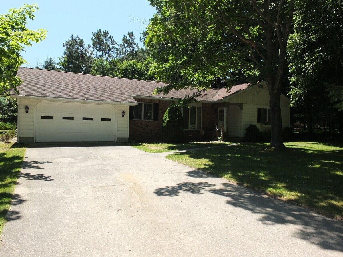 A two-story house with a garage, a driveway, and a lawn.