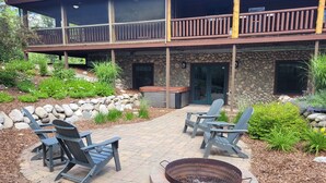 A stone building with a balcony, outdoor seating, and a fire pit. - Weatherwood - Gorgeous Luxury Log Cabin with Spa, Sauna, & Games!  8 minutes from Crystal Mountain! (Copemish)