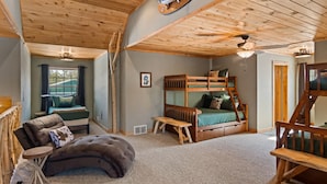 A cozy cabin interior with a bunk bed, a cushioned seating area, and a wooden ceiling. - Weatherwood - Gorgeous Luxury Log Cabin with Spa, Sauna, & Games!  8 minutes from Crystal Mountain! (Copemish)