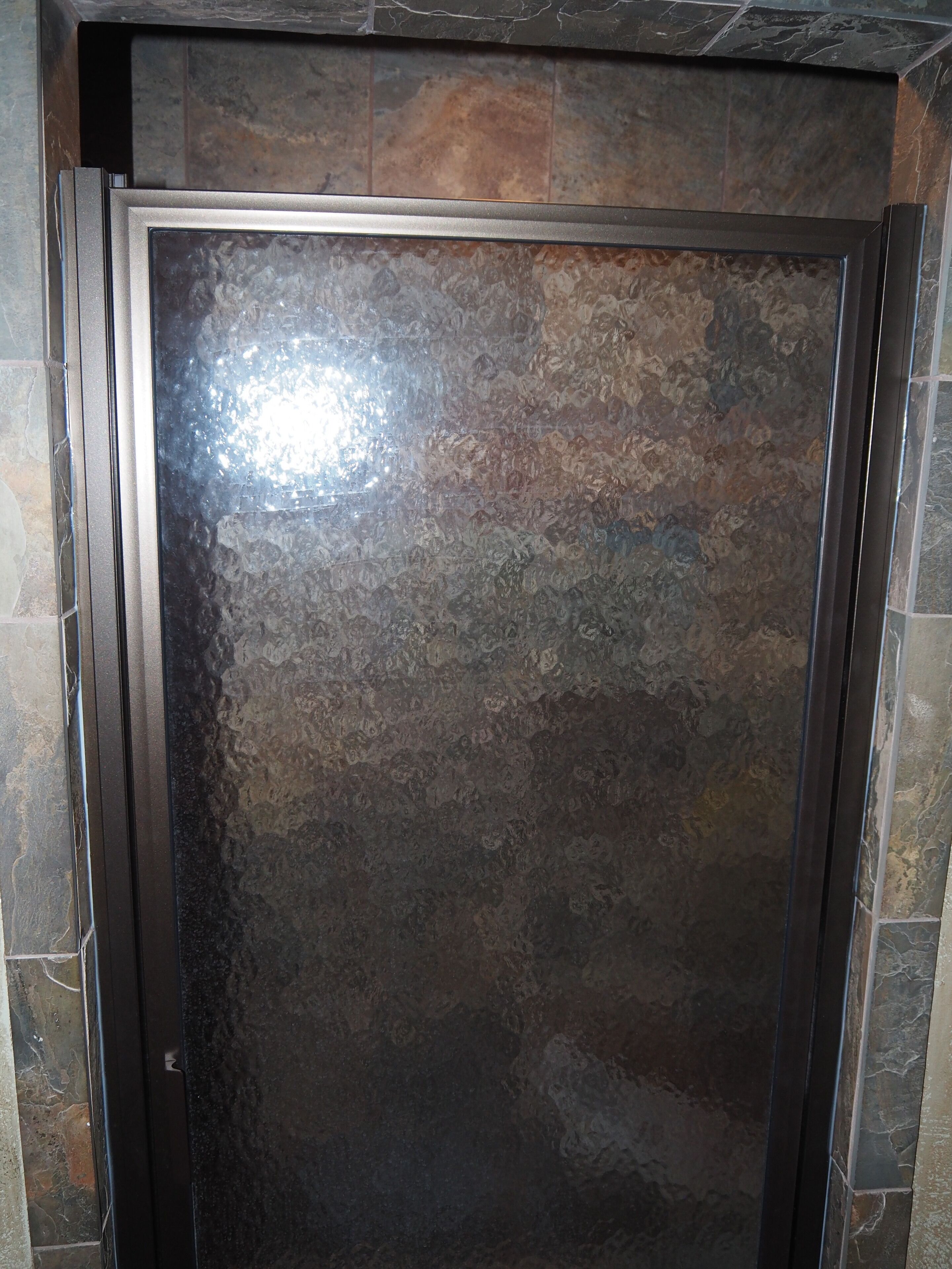 A metallic door with a textured surface, set within a stone wall.