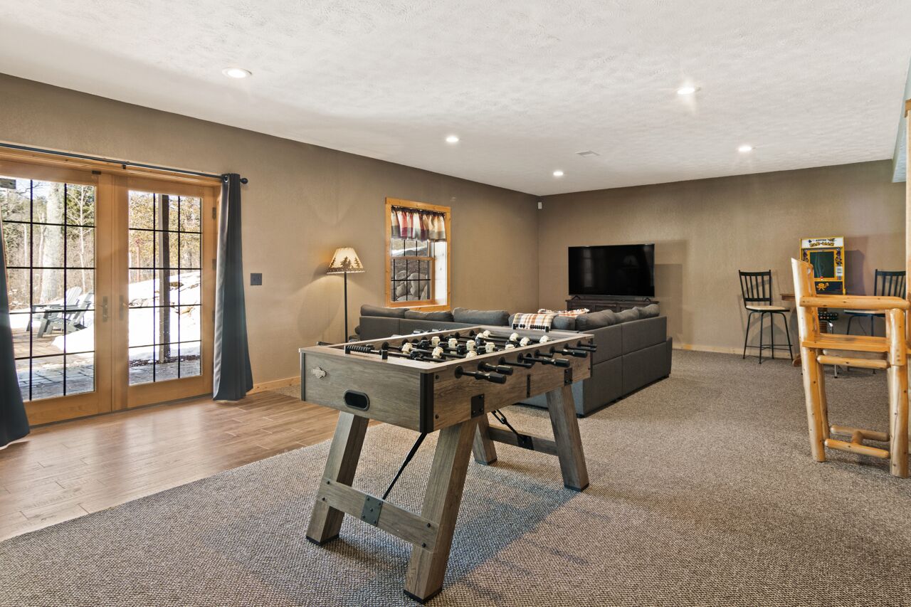 Una sala de estar con una mesa de fútbol de mesa, un sofá, un televisor y una silla de madera.