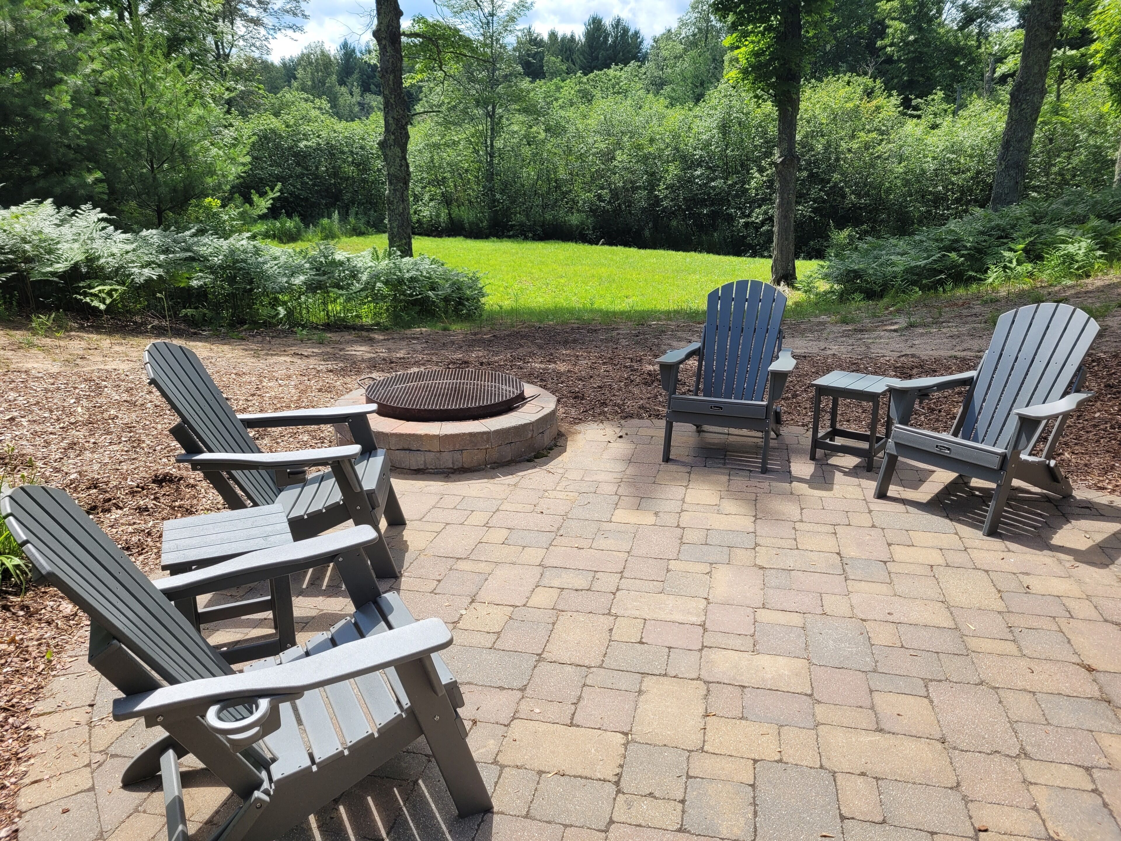 An outdoor seating area with Adirondack chairs and a fire pit.