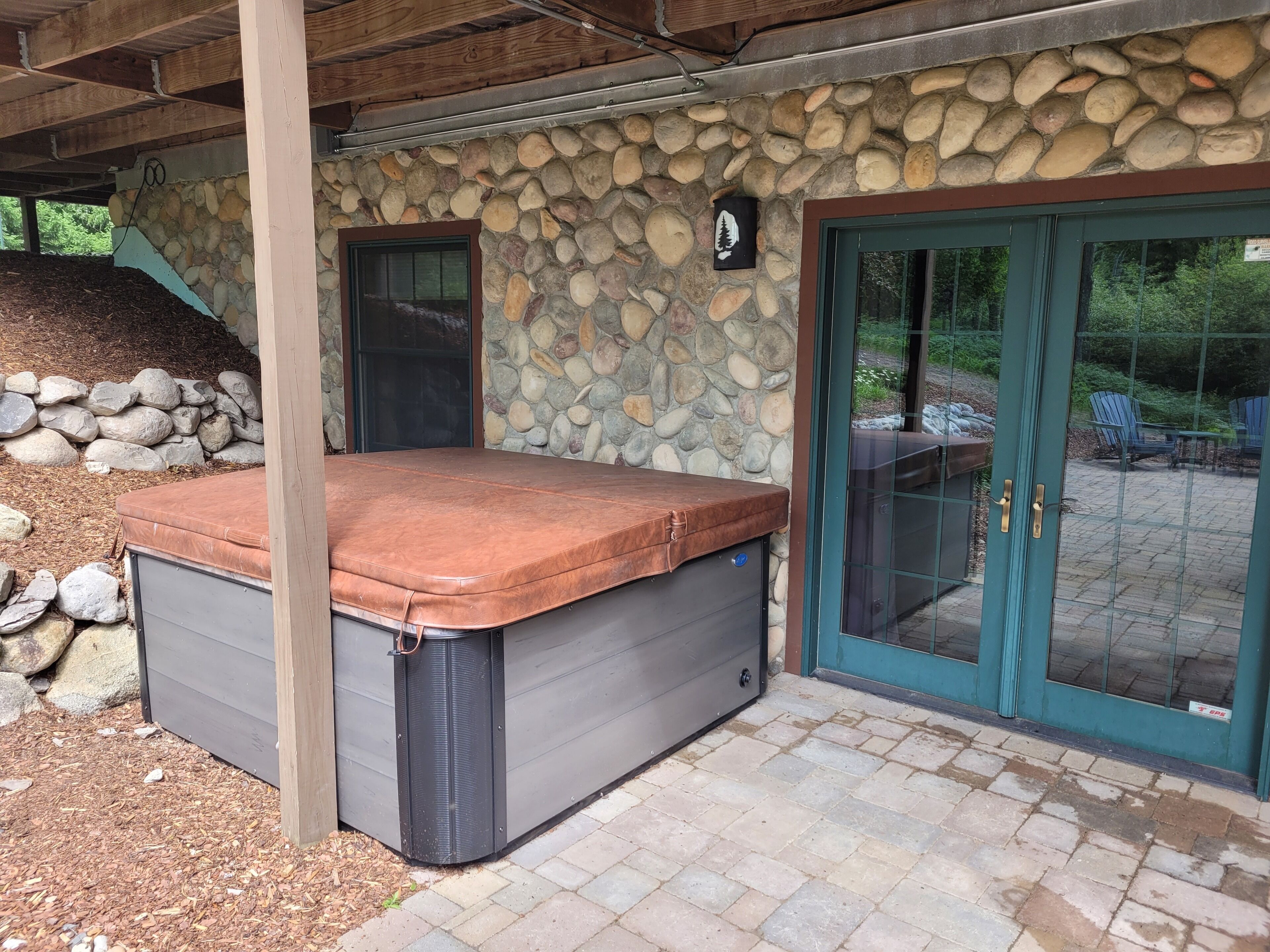 A spa-like hot tub area with a stone wall and a wooden ceiling.