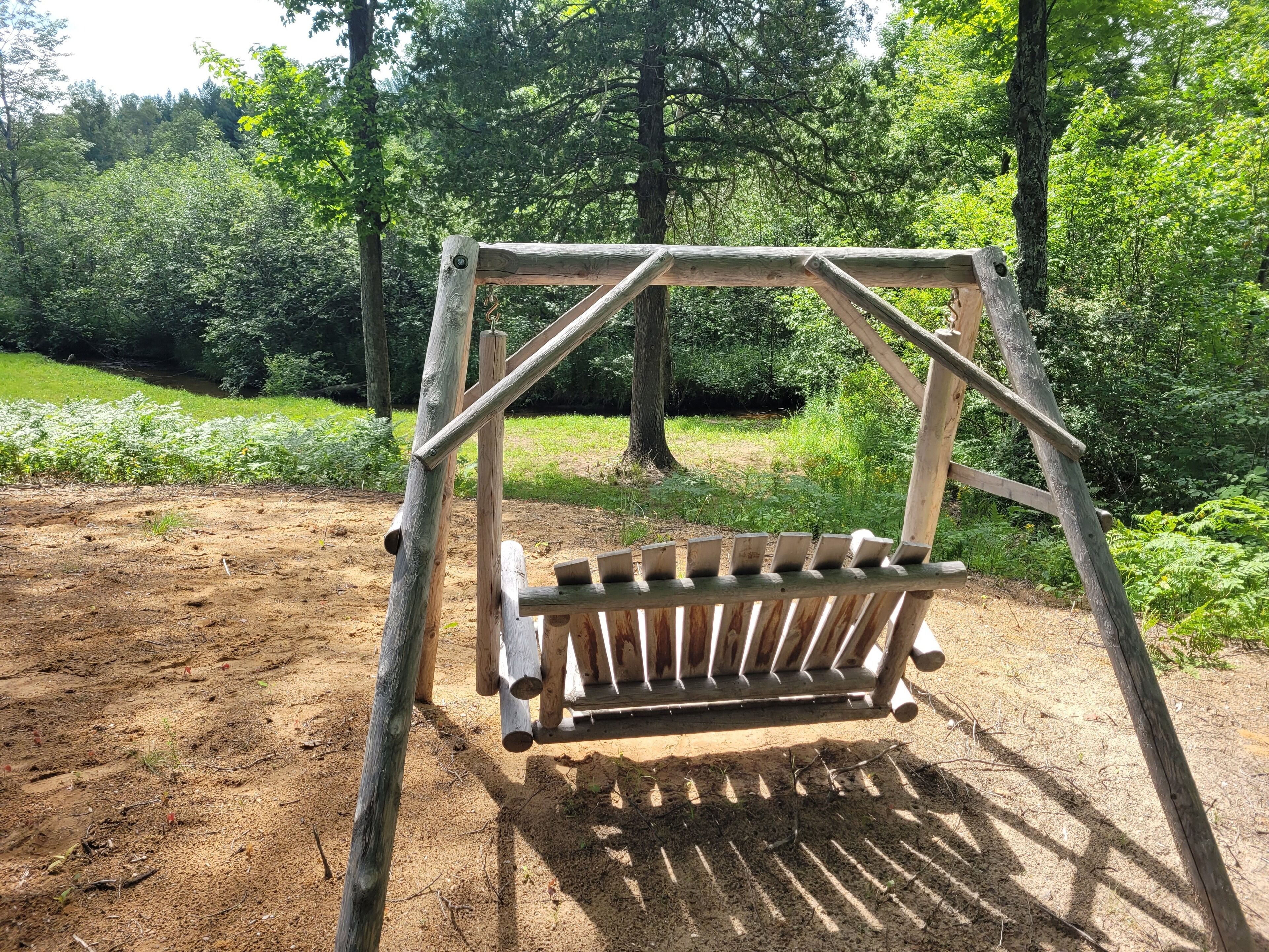 A wooden swing set in a forested area.