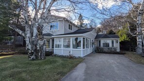 A two-story house with a covered porch and a stone foundation.