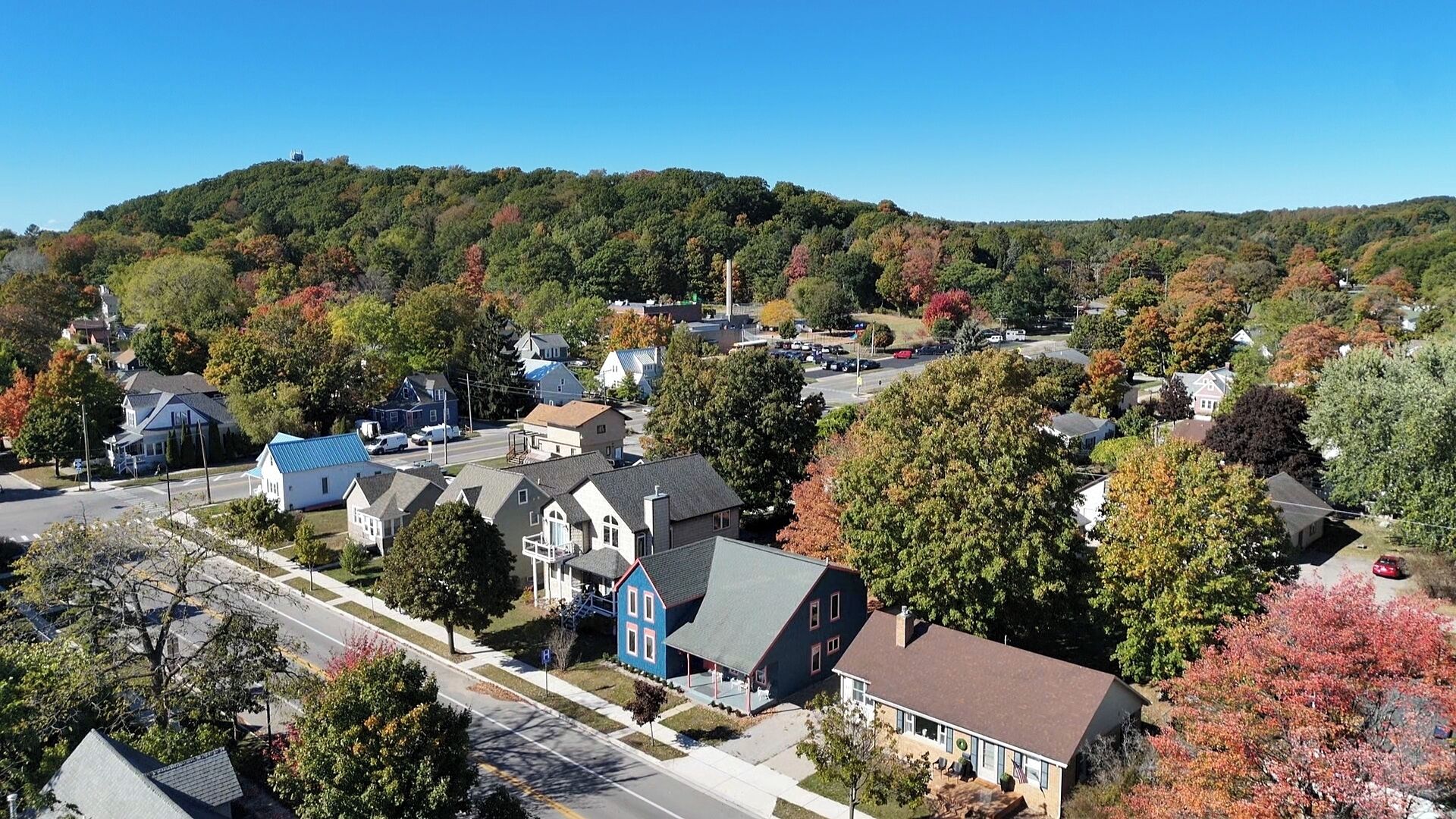 A residential area with houses, a main road, and a hill with trees.
