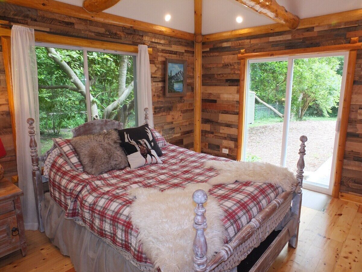 Une chambre à coucher en bois, avec un lit, des rideaux et une fenêtre.