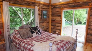 Une chambre à coucher en bois, avec un lit, des rideaux et une fenêtre.