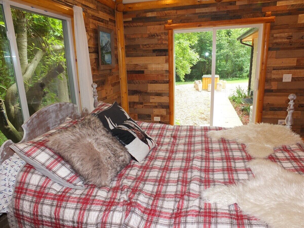 Une chambre à coucher avec un lit, une fenêtre et une porte donnant sur l’extérieur.
