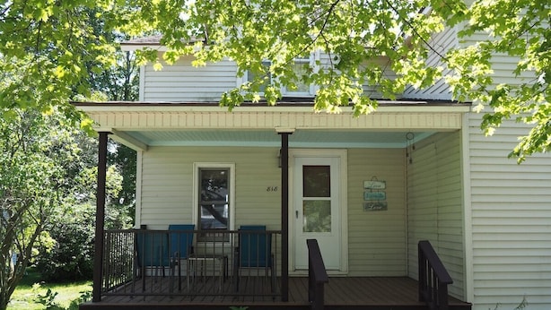 A house with a porch, a door, and a small table with chairs. - The Cute & Cozy - Lower Apt. - GREAT LOCATION!  WALK TO DOWNTOWN AND LAKE MICHIGAN! (Frankfort)